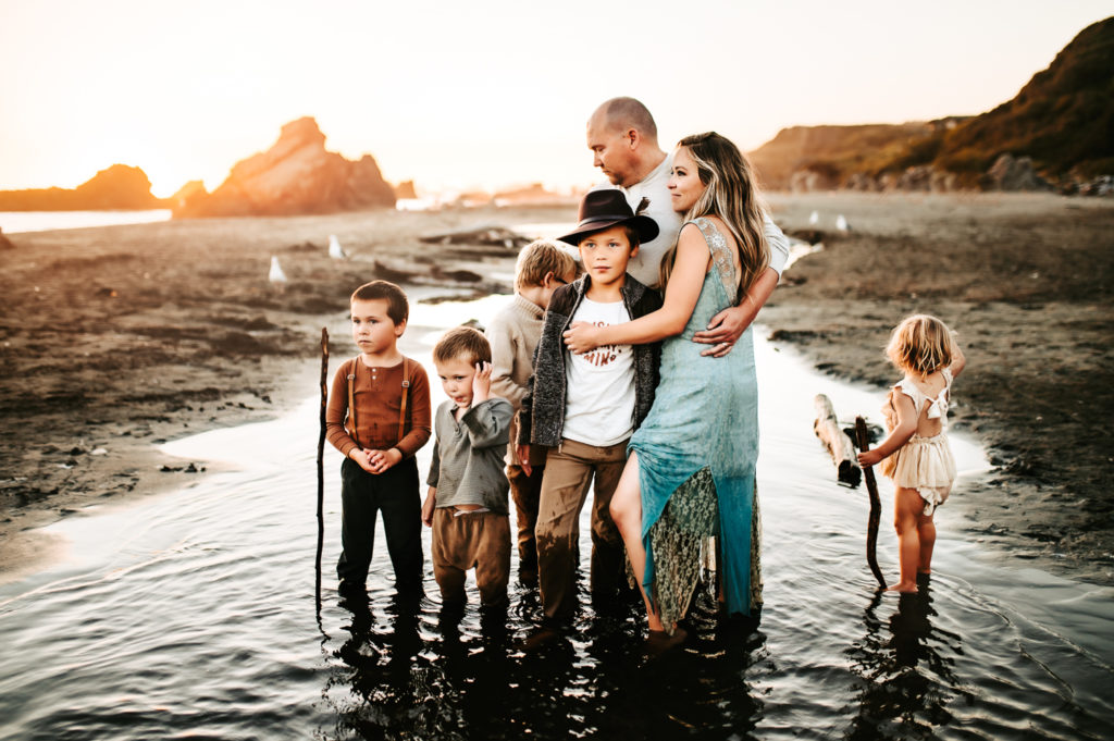 Family Photographer, a mother and father stand with their five young children at the beach